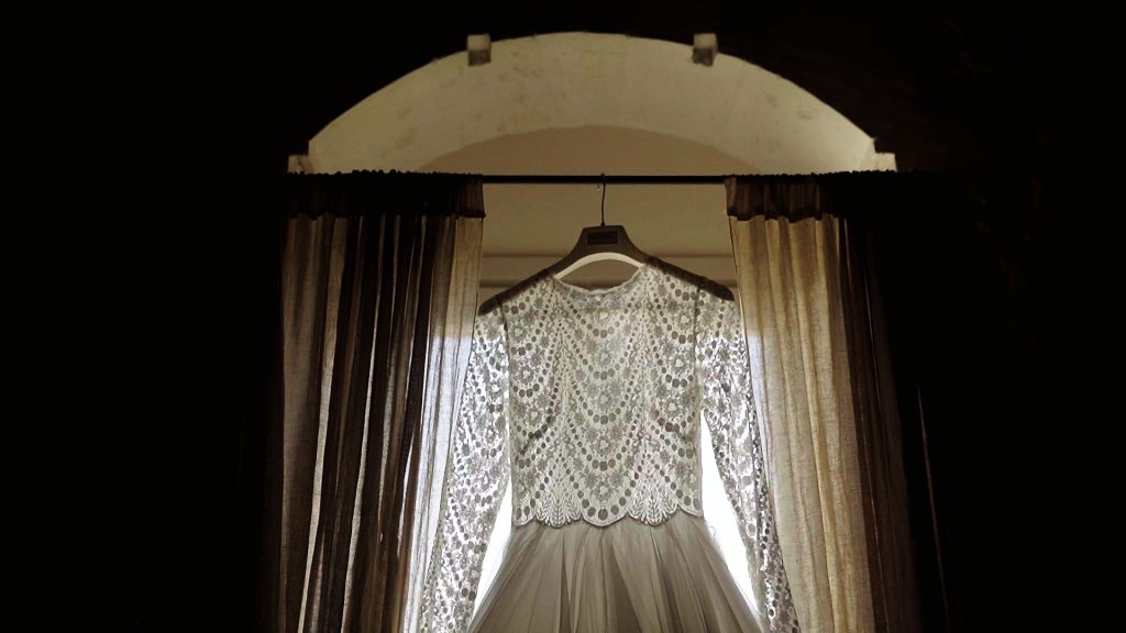 bride's dress hanging on a window with arch