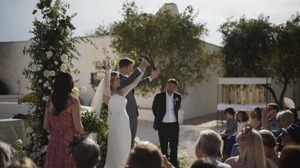 the newlyweds rejoice, smiling at the guests because they have just been proclaimed husband and wife during their destination wedding