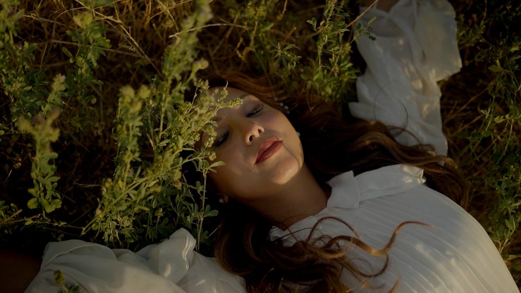 the bride lying with her eyes closed in the grass of the Tuscan hills at sunset during her save the date for their destination wedding in Tuscany