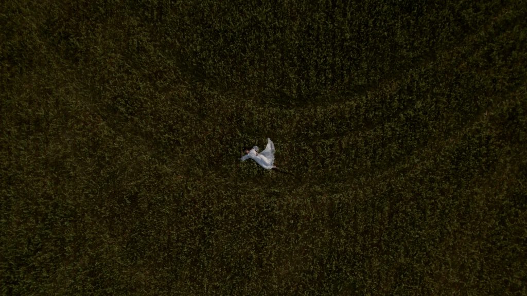aerial view of the bride lying on the green lawn of a Tuscan hill