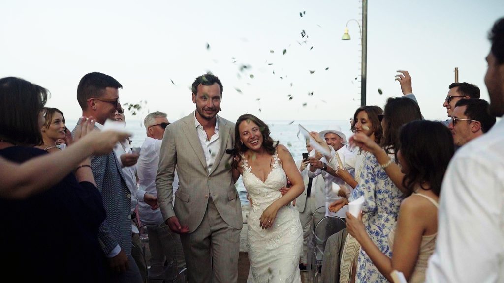 the bride and groom walk down the aisle smiling while the guests throw rice