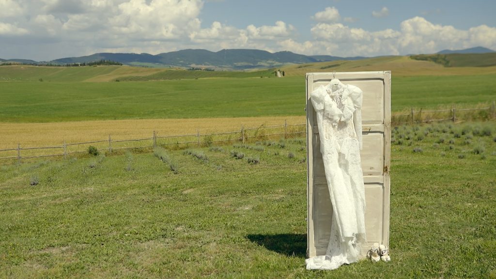 wedding dress on a white door with the background of the green Tuscan hills