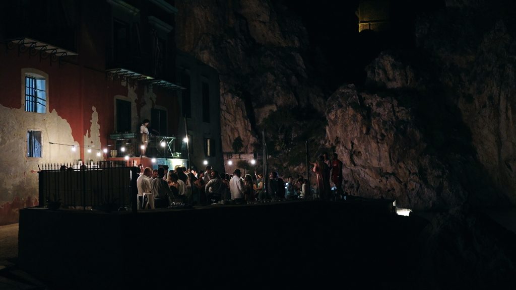 overview of the party after dinner with the DJ set on the seashore among the rocks overlooking the sea